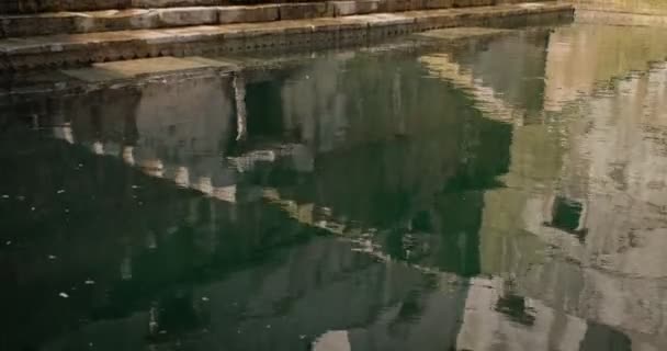 Almacenamiento de agua dentro del pozo Toorji Ka Jhalra Baoli, una de las fuentes de agua en Jodhpur, Rajastán, India. Día soleado, olas de agua reflejan las paredes de la piscina. Cámara vertical pan
 - Metraje, vídeo