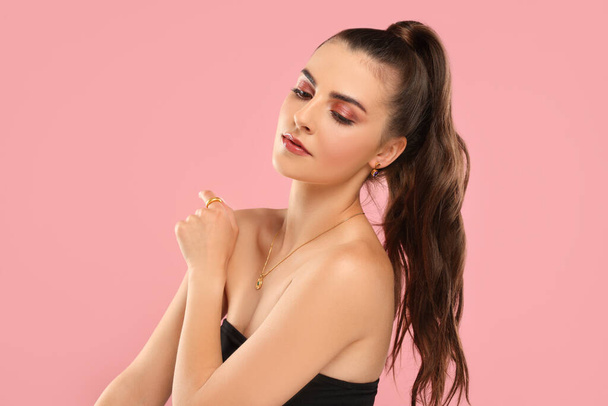 Beautiful woman with elegant jewelry on pink background - Foto, afbeelding