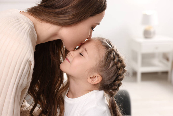 Happy mother kissing her cute daughter at home - Fotó, kép