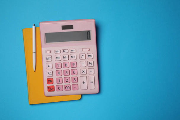 Calculator, notebook and pen on light blue background, flat lay with space for text - Foto, afbeelding