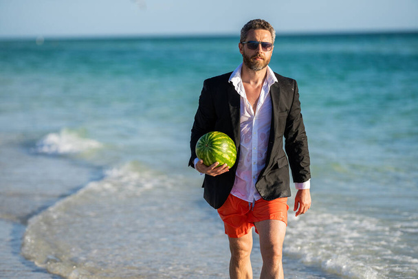 Successful businessman man on summer business vacation at sea beach with watermelon, copy space. - Fotoğraf, Görsel