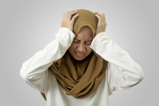Portrait of sad young Asian muslim girl wearing hijab crying against red background, despression concept - Фото, зображення