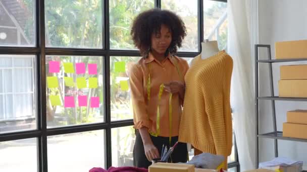 Όμορφη νεαρή Αμερικανίδα Αφρικανή επαγγελματίας στυλίστας που εργάζεται στο εσωτερικό του στούντιο σχεδιασμού. έννοια σχεδιαστής μόδας. - Πλάνα, βίντεο