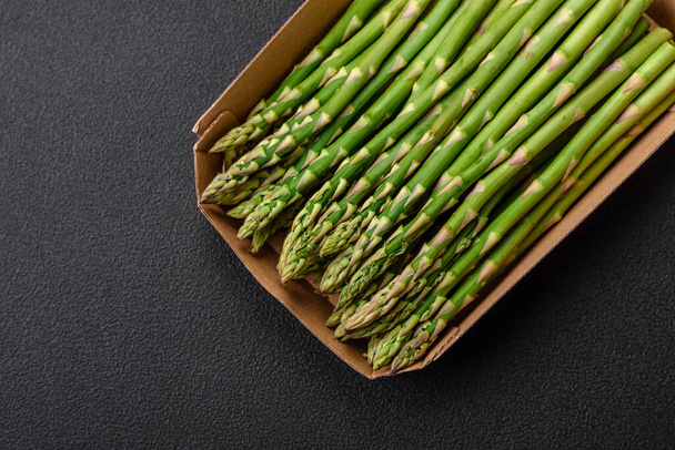 Delicious fresh sprigs of asparagus on a dark textured background. Ingredients for a healthy vegetarian meal - Valokuva, kuva