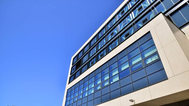 Moderni toimistorakennus sinistä taivasta vastaan. Modernin lasirakennuksen ikkunat. Katse ylös liikerakennuksiin. - Valokuva, kuva