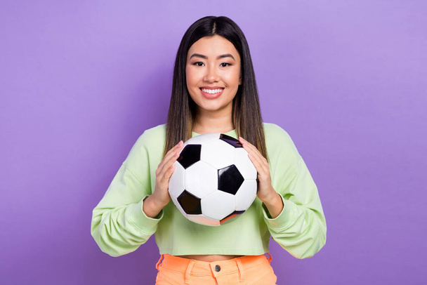 Photo of good mood positive woman with dyed hairdo dressed green clothes arms holding football ball isolated on purple color background. - Фото, изображение