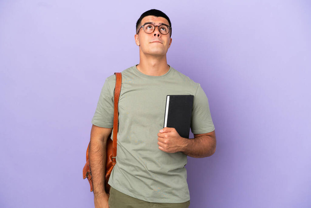 Handsome student man over isolated background and looking up - Photo, Image