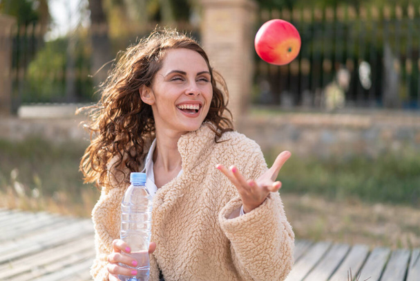 若い白人女性が屋外でリンゴと水のボトルで - 写真・画像