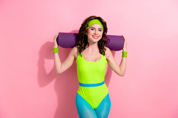 Photo of cheerful sportive fitness instructor hold roll carpet shoulders wear green blue bodysuit isolated on pink color background. - Photo, image