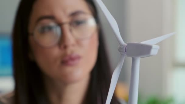 Крупный план женщины-инженера, смотрящей на пластиковую модель ветряной турбины во время работы над проектом клиента в офисе - Кадры, видео