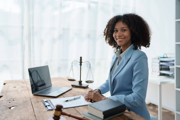 Young African American lawyer studying a case for a client and signing a legal contract to fight her opponent in court. Legal and lawyer concepts - Фото, изображение