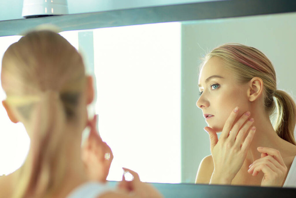 Face of young beautiful healthy woman and reflection in the mirror. - 写真・画像