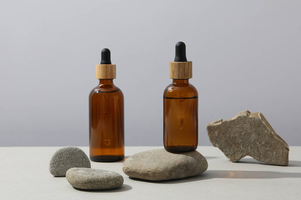 Stones and bottles with serum on gray background - Photo, image