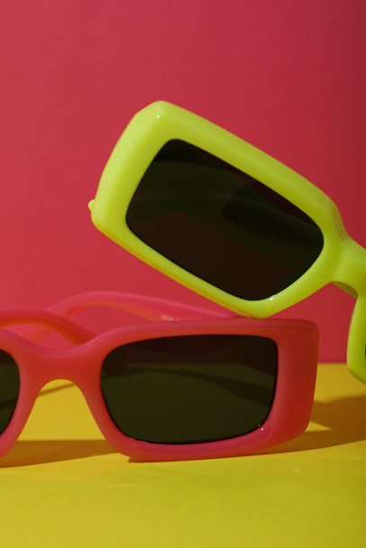 Κόκκινα και κίτρινα γυαλιά ηλίου σε κόκκινο και κίτρινο φόντο, κοντά - Φωτογραφία, εικόνα