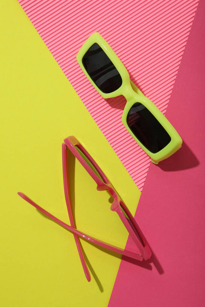 Κίτρινα και ροζ γυαλιά σε κίτρινο και ροζ φόντο, πάνω όψη - Φωτογραφία, εικόνα