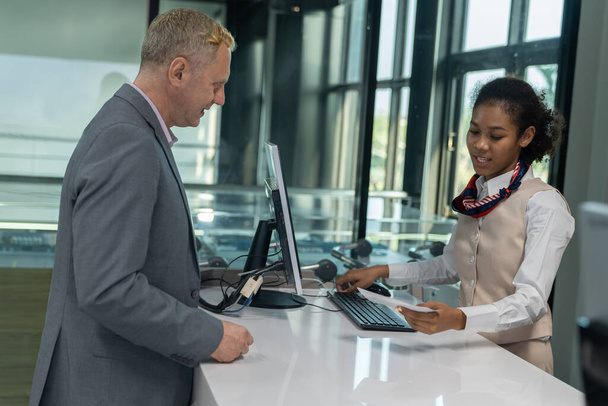 Businessman check-in at hotel counter. Female receptionist informs the business man about staying in the hotel. Concept of a reception service counter providing customer information. - Foto, Imagem