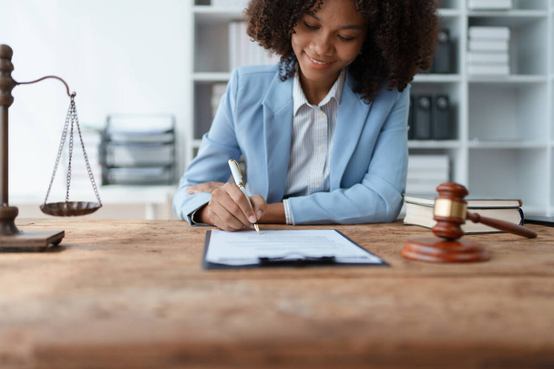 Young African American lawyer studying a case for a client and signing a legal contract to fight her opponent in court. Legal and lawyer concepts - Foto, Bild
