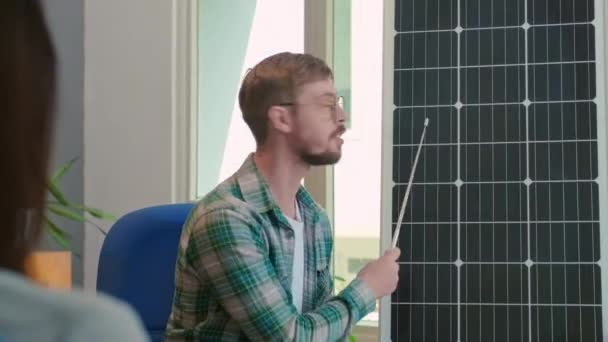 Por encima de la vista del hombro del cliente mirando al ingeniero mostrando el panel de energía solar en la oficina - Metraje, vídeo