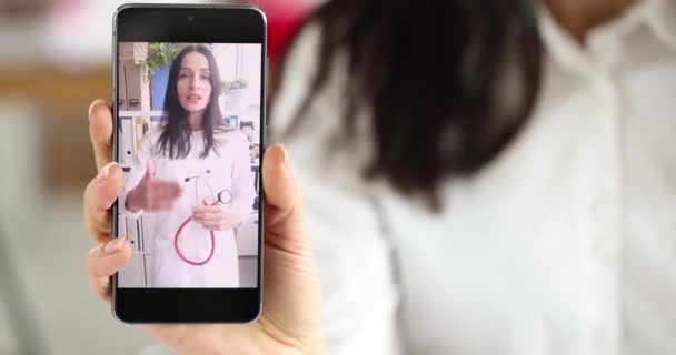 Frau mit Handy in der Hand, wo Arzt auf Video-Link 4k-Film spricht. Konzept medizinischer Webinare - Filmmaterial, Video