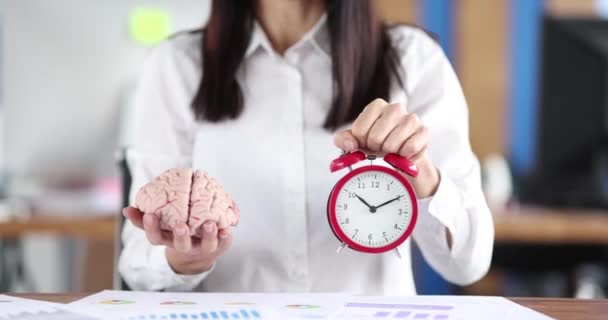Bizneswoman trzymając sztuczny mock ludzkiego mózgu i czerwony budzik w rękach zbliżenie 4k film slow motion. Koncepcja strategii biznesu - Materiał filmowy, wideo