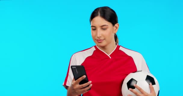 Woman, sports and video call in studio, talk and football celebration, excited and happy by blue background. Girl, professional soccer player and ball with webinar, communication or chat with success. - Footage, Video
