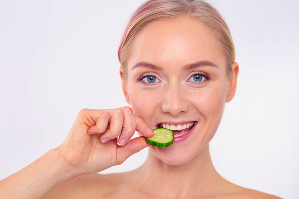 Young beautiful woman with cucumber slices on white background - Foto, Imagem