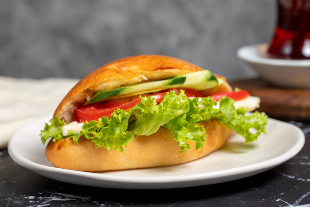 Sandwich with cheese, tomato, cucumber and lettuce. Delicious sandwich on dark background. Close up - Photo, image