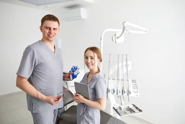 Dentista y asistente en la sala de examen sonriendo
 - Foto, Imagen