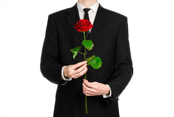 Valentine's Day and Women's Day theme: man's hand in a suit holding a red rose isolated on white background in studio - Фото, изображение