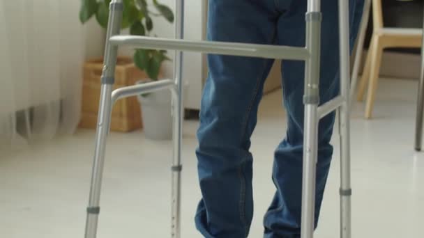 Oudere man met een handicap met behulp van walker tijdens het lopen door zijn huis - Video