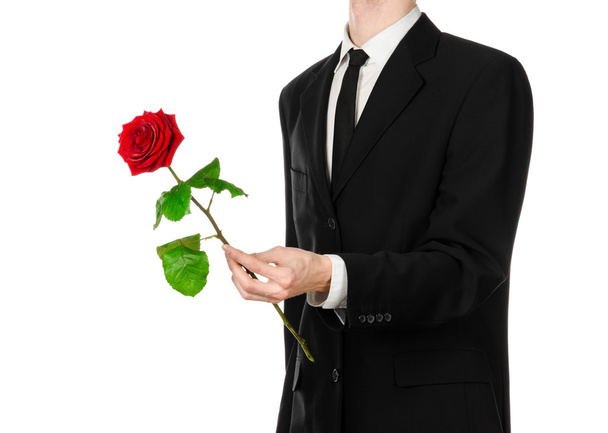 Valentine's Day and Women's Day theme: man's hand in a suit holding a red rose isolated on white background in studio - Zdjęcie, obraz