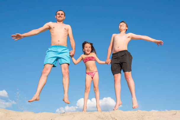 Happy family having fun playing on the beach on summer vacation. Concept about sports and active games in summer - Foto, afbeelding