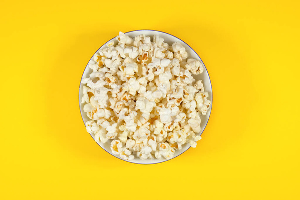 Teller mit frischem Popcorn auf gelbem Hintergrund. Kino- und Unterhaltungskonzept. Ansicht von oben. - Foto, Bild