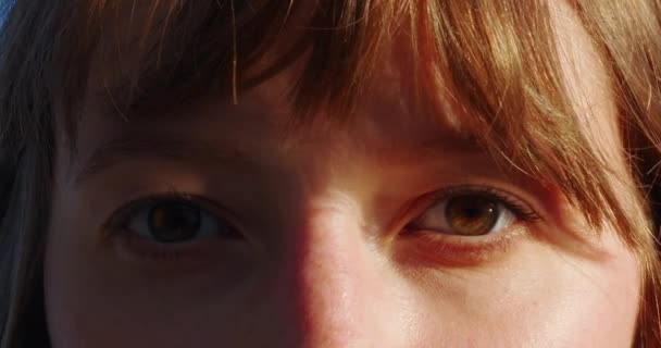 Közelkép egy barna szemű nőről fénysmink nyitással és a nap lassított felvételével. A vörös hajú lányok szeme nyitva. Lassú mozgás. 120-as egység. Makro szemfotózás. Egy gyönyörű arc. - Felvétel, videó