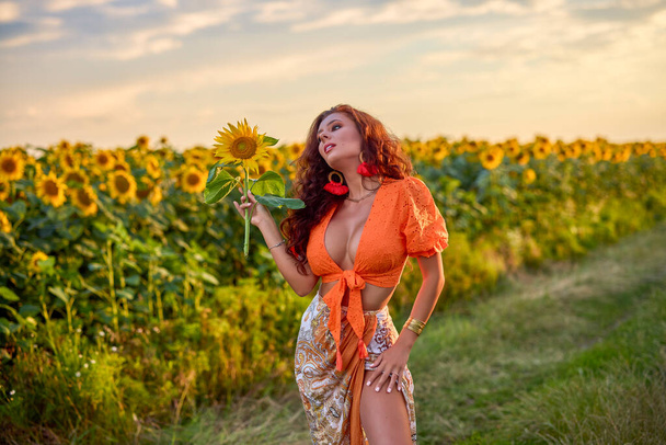 retrato de una hermosa mujer cerca de un campo de girasoles en un día soleado al atardecer. - Foto, Imagen