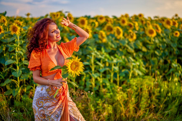 retrato de una hermosa mujer cerca de un campo de girasoles en un día soleado al atardecer. - Foto, Imagen