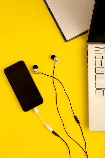 moderni musta älypuhelin ja kuulokkeet, kannettava tietokone pöydällä  - Valokuva, kuva