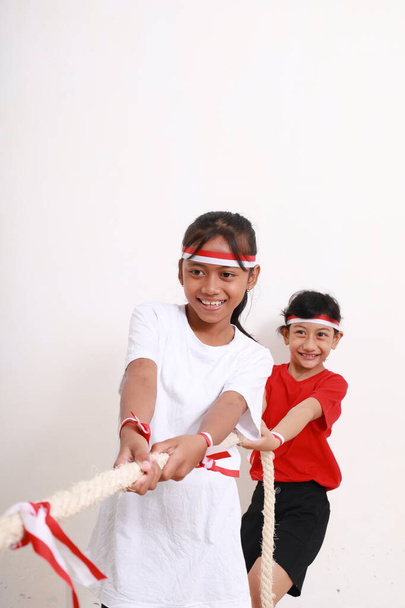 Dos niñas celebrando el día de la independencia de Indonesia con tirón de juego de guerra. Aislado sobre blanco - Foto, imagen