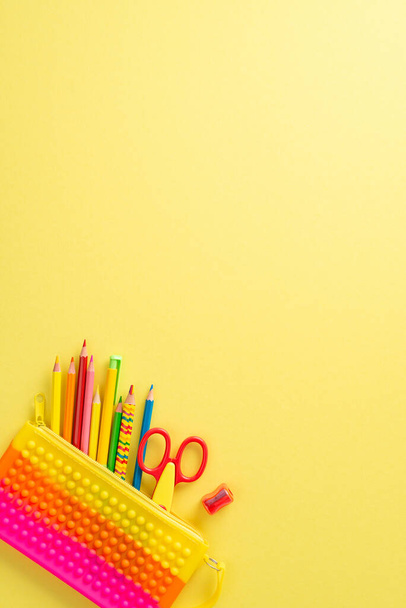 Immerse in the joy of education for small kids through this top view photograph: a captivating display of vibrant kid stationery on an isolated yellow backdrop, offering copyspace for text or adverts - Photo, Image