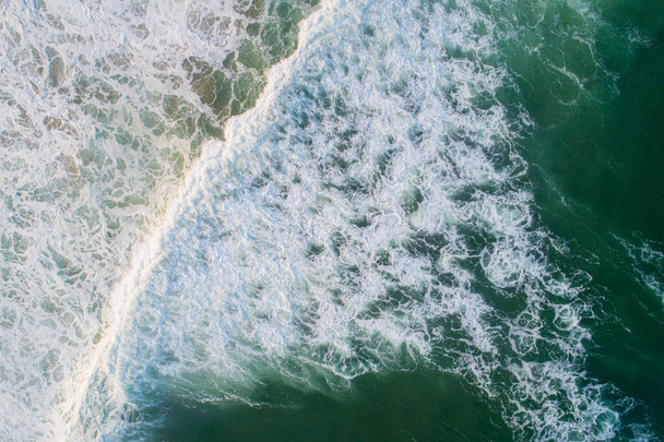 Aerial view of the foam crashing waves on shore - Fotoğraf, Görsel