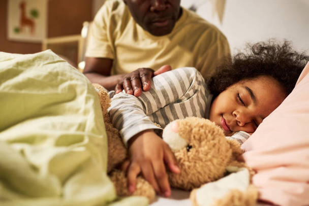 アフリカ系アメリカ人の父親は赤ん坊をベッドに寝かしつけて話をした - 写真・画像