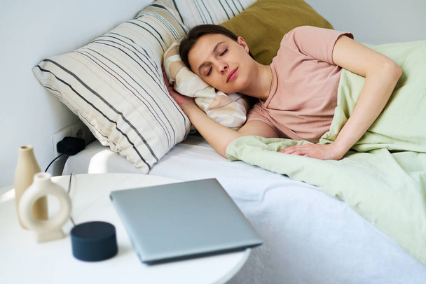 Giovane donna che riposa sul letto nella sua camera da letto dopo aver usato gadget - Foto, immagini