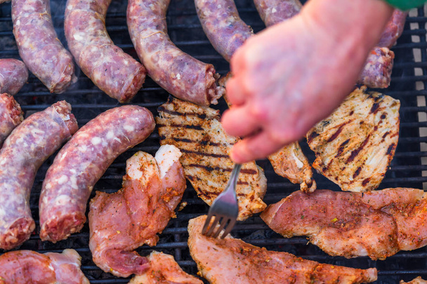 Grilling sausages and pork chops on barbecue grill. BBQ in the garden - Photo, Image
