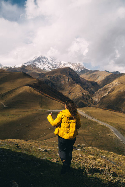 Rückansicht einer jungen Frau blickt auf den Berg Kazbek in Georgien - Foto, Bild
