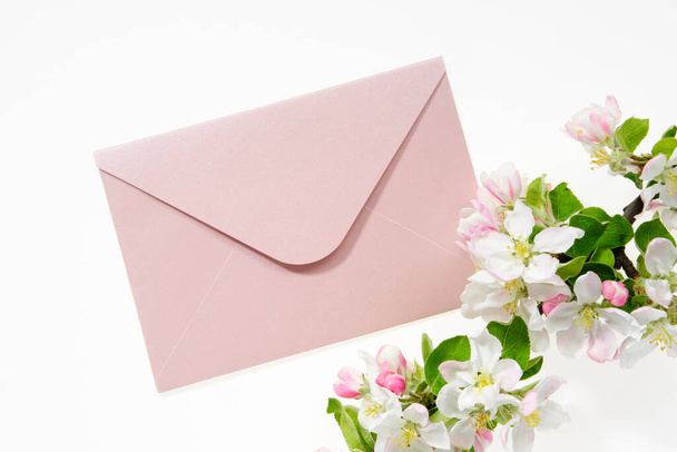 Pink envelope with wedding invitation card or birthday letter decorated with branch of blossom apple tree. Flat lay. Top view. - Fotó, kép