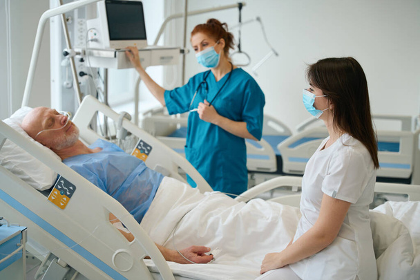 Women physicians attending their male patient who lying in hospital bed in the resuscitation - Zdjęcie, obraz