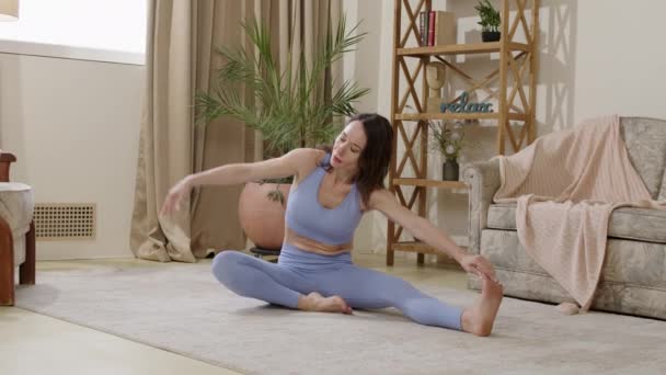 Relaxed sportswoman leaning on her back, practicing pilates exercises. Flexible girl practicing gymnastics wearing sports clothes. Young woman who takes care of her body and stretches her muscles - Footage, Video