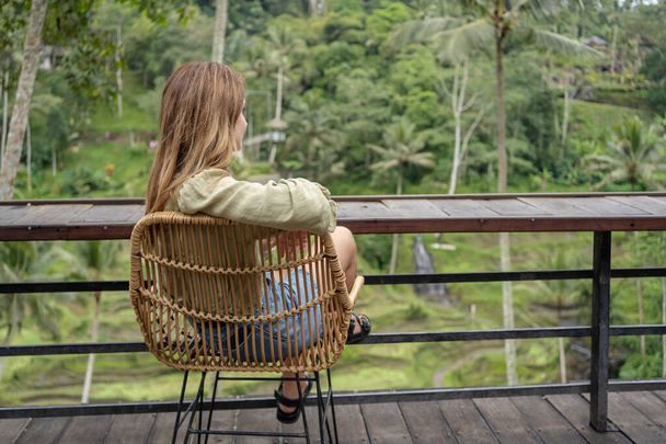 Woman sit on wicker chairs at outdoor terrace with view of rice terraces . - Foto, Bild