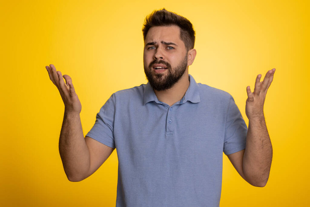 What Why. Sincere irritated caucasian man raising hands in indignant expression asking reason of failure demonstrating disbelief irritation by trouble. Handsome confused guy on yellow background - Foto, Bild
