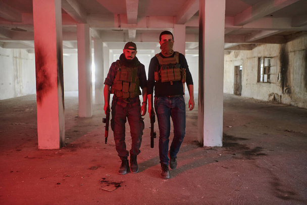 Ein verlassenes Gebäude dient als Hochburg für ein Team von Terroristen, die ihr besetztes Territorium mit Waffen und militärischer Ausrüstung erbittert bewachen..  - Foto, Bild